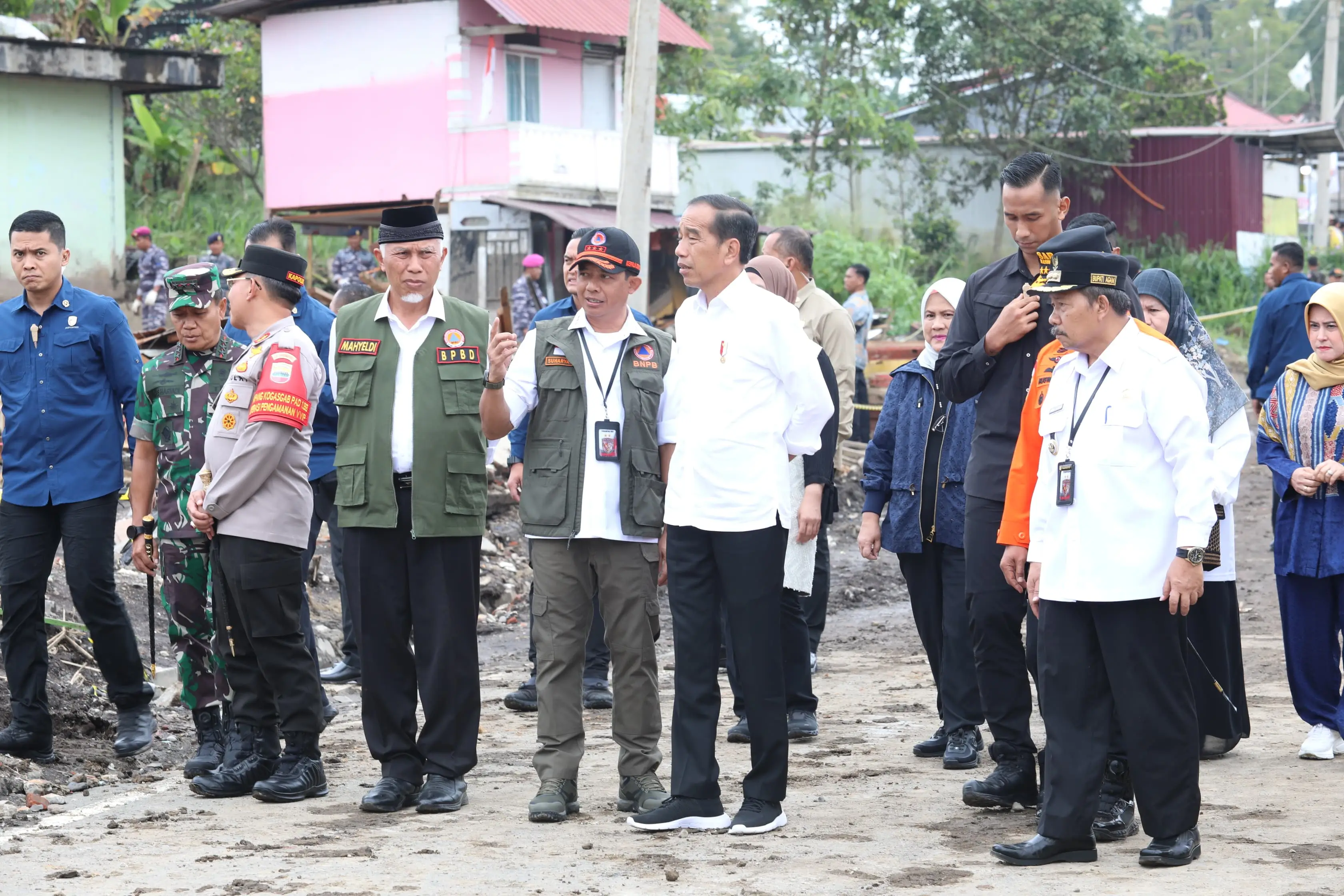 Kepala BNPB Letjen TNI Suharyanto, S.Sos., M.M., (rompi hijau dengan topi hitam) menceritakan perkembangan penanganan kepada Presiden Ir. Joko Widodo saat meninjau lokasi terdampak banjir lahar hujan Gunungapi Marapi di Nagari Bukit Batabuah, Kabupaten Agam, Sumatera Barat pada Selasa (21/5).